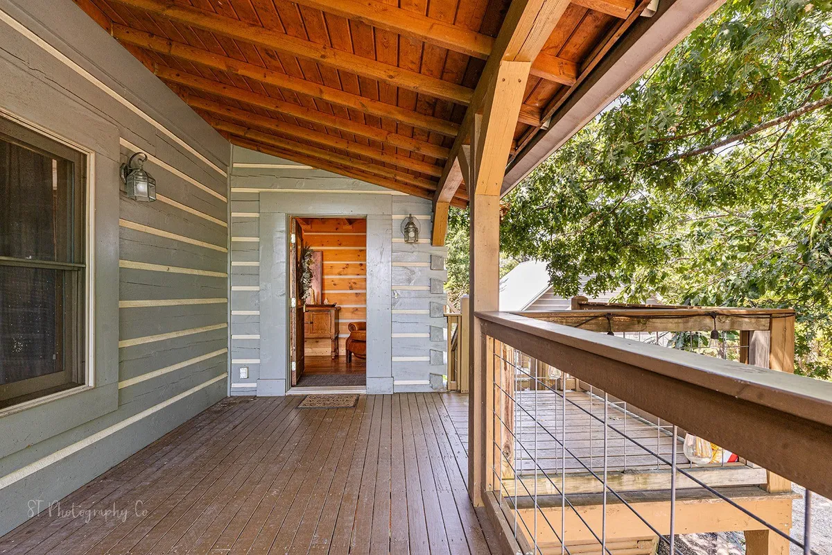 A welcoming porch with wooden railings and exposed beams, leading to the entrance of the Lodge. The setting is inviting, with space to relax and enjoy views, suggesting both an arrival moment and ongoing outdoor enjoyment.