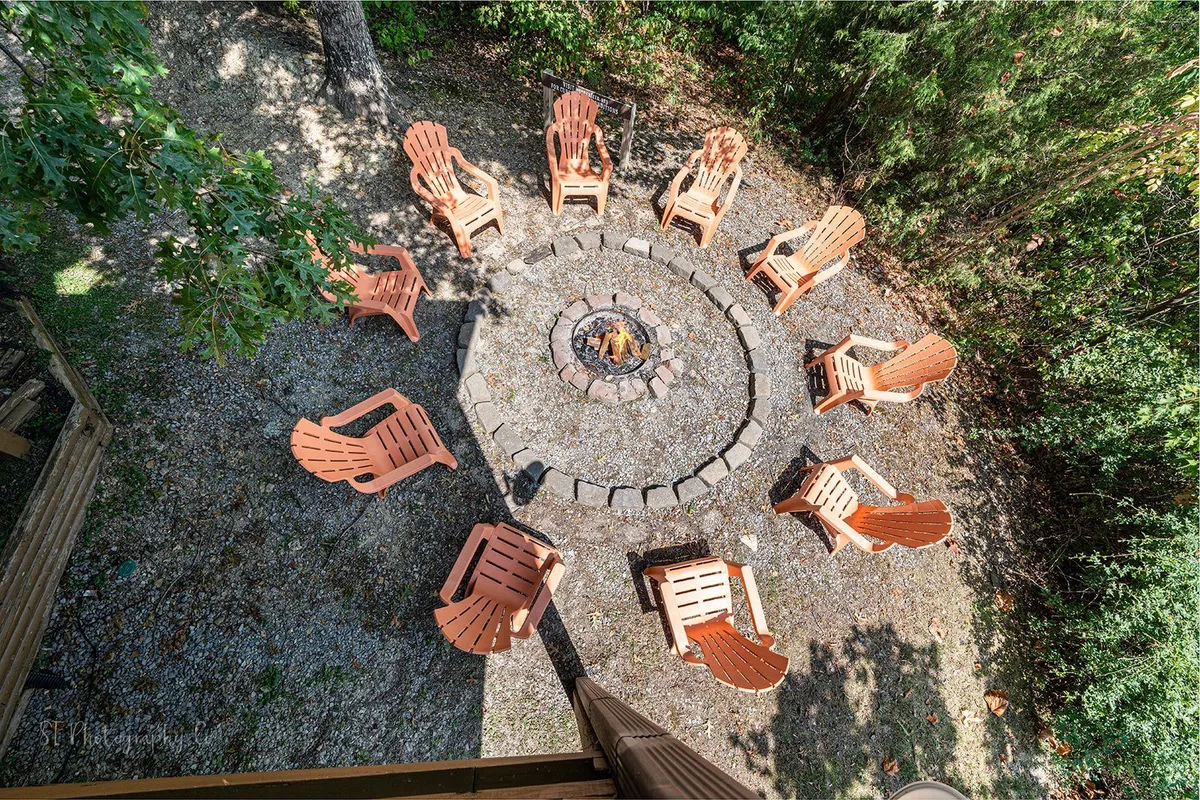 A cozy fire pit area surrounded by Adirondack chairs, set amidst lush greenery. The scene speaks to the communal, outdoor evenings spent sharing stories, roasting marshmallows, and making memories under the stars.